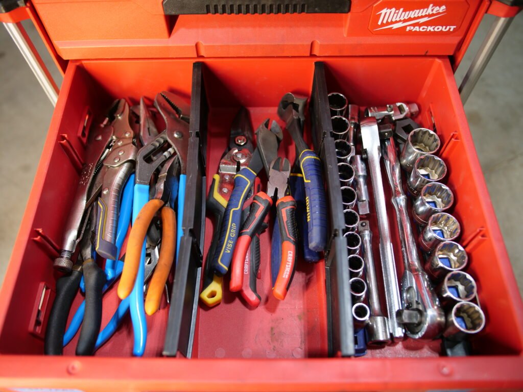 Close-up of a Milwaukee Packout drawer showcasing a selection of pliers, cutters, and a 1/2 inch socket set.