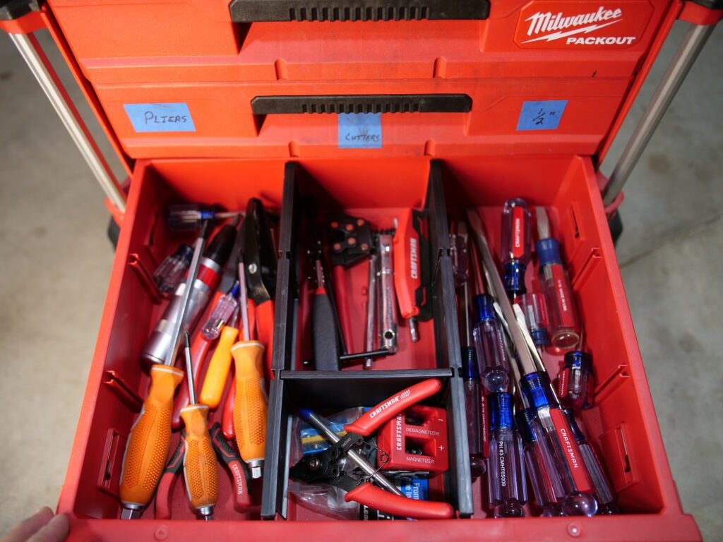 Close-up of a Milwaukee Packout drawer showcasing SL (slotted), Phillips screwdrivers, and various ATV tools, including chain and cable tools.