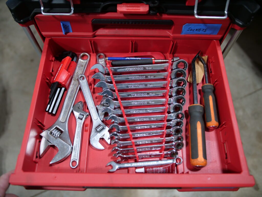 Close-up of a Milwaukee Packout drawer showcasing a neatly arranged set of wrenches, pry bars, adjustable wrenches, and allen keys.