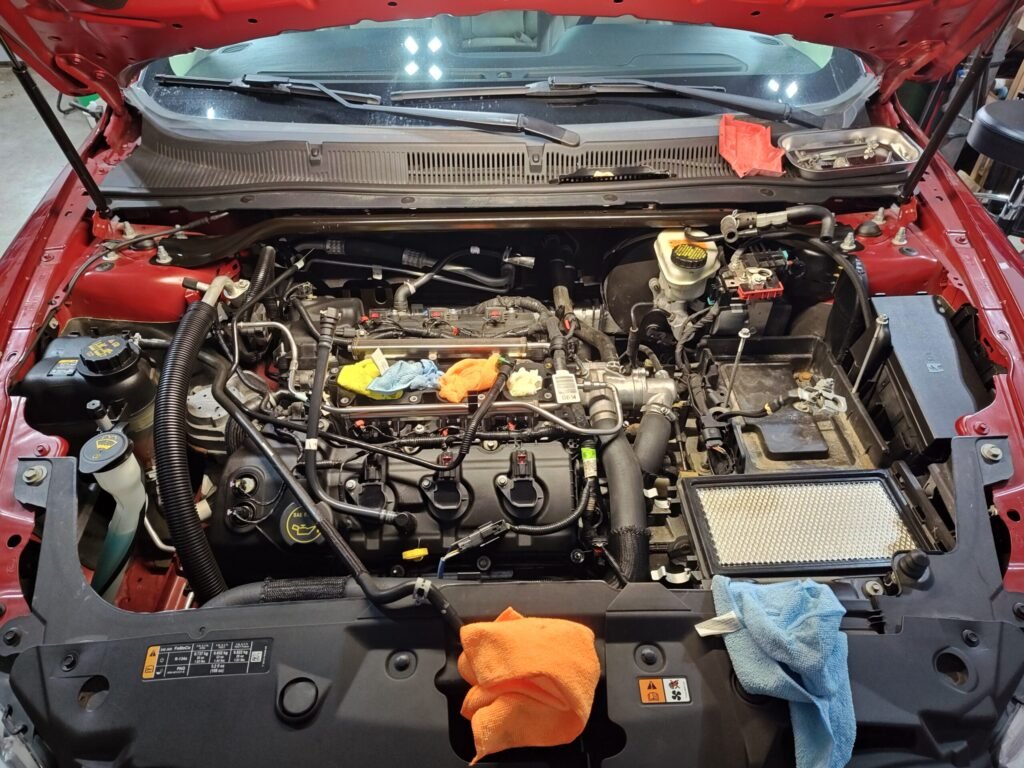 2015 Ford Taurus engine with intake manifold removed, exposing coil packs, spark plugs, and fuel injectors during service