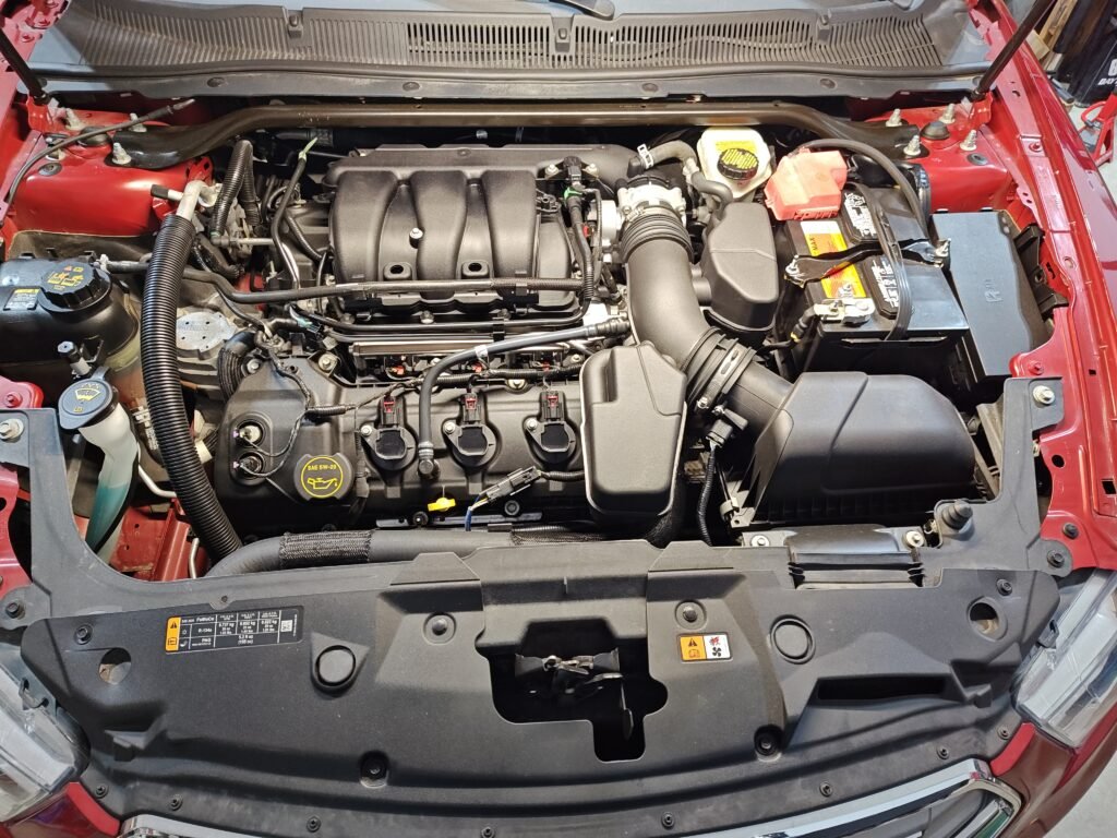 2015 Ford Taurus engine bay showing 3.5L V6 engine before spark plug, coil pack, and injector replacement