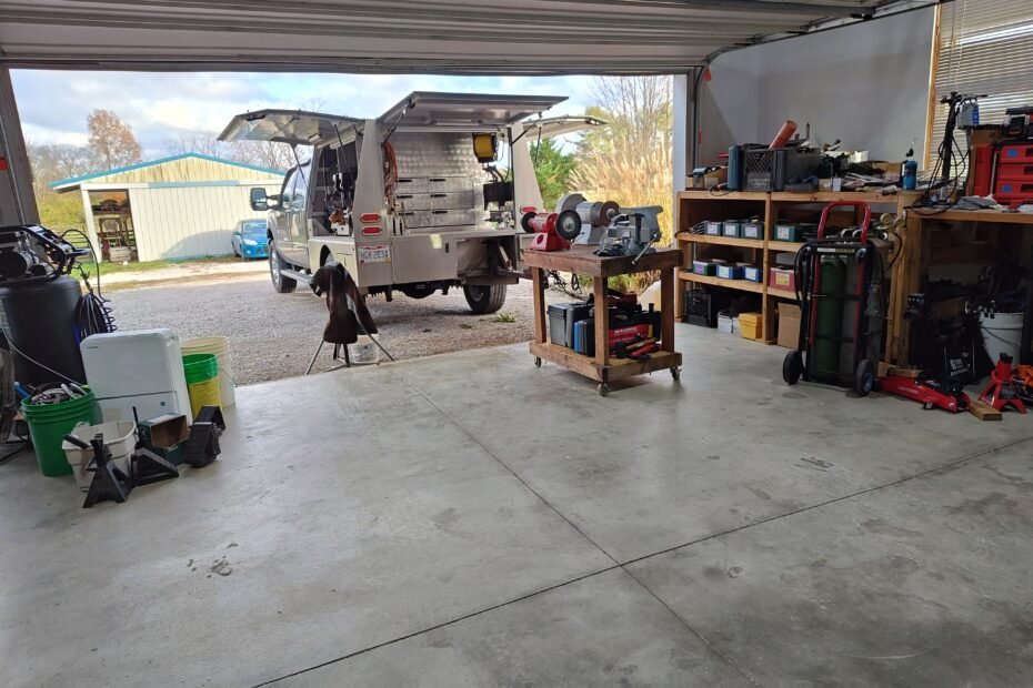 Professional farrier's garage workshop showing Ford Super Duty with Bay Horse aluminum body backed up to organized workspace, featuring mobile grinding station and tool storage